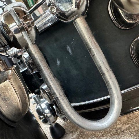 A U-shaped aluminum rod linking the snare hoop and the floor-tom hoop.