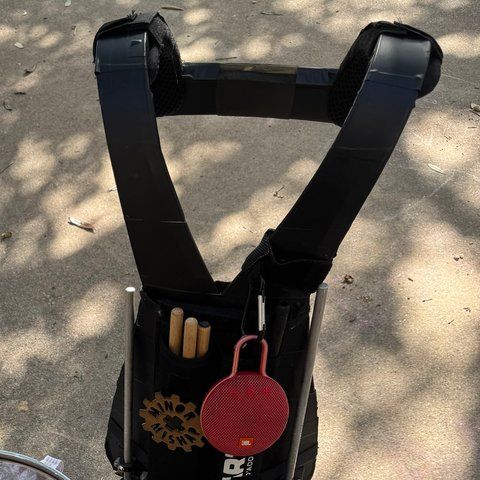 The black-taped REMO marching harness with its shoulder straps, standing behind the drums.