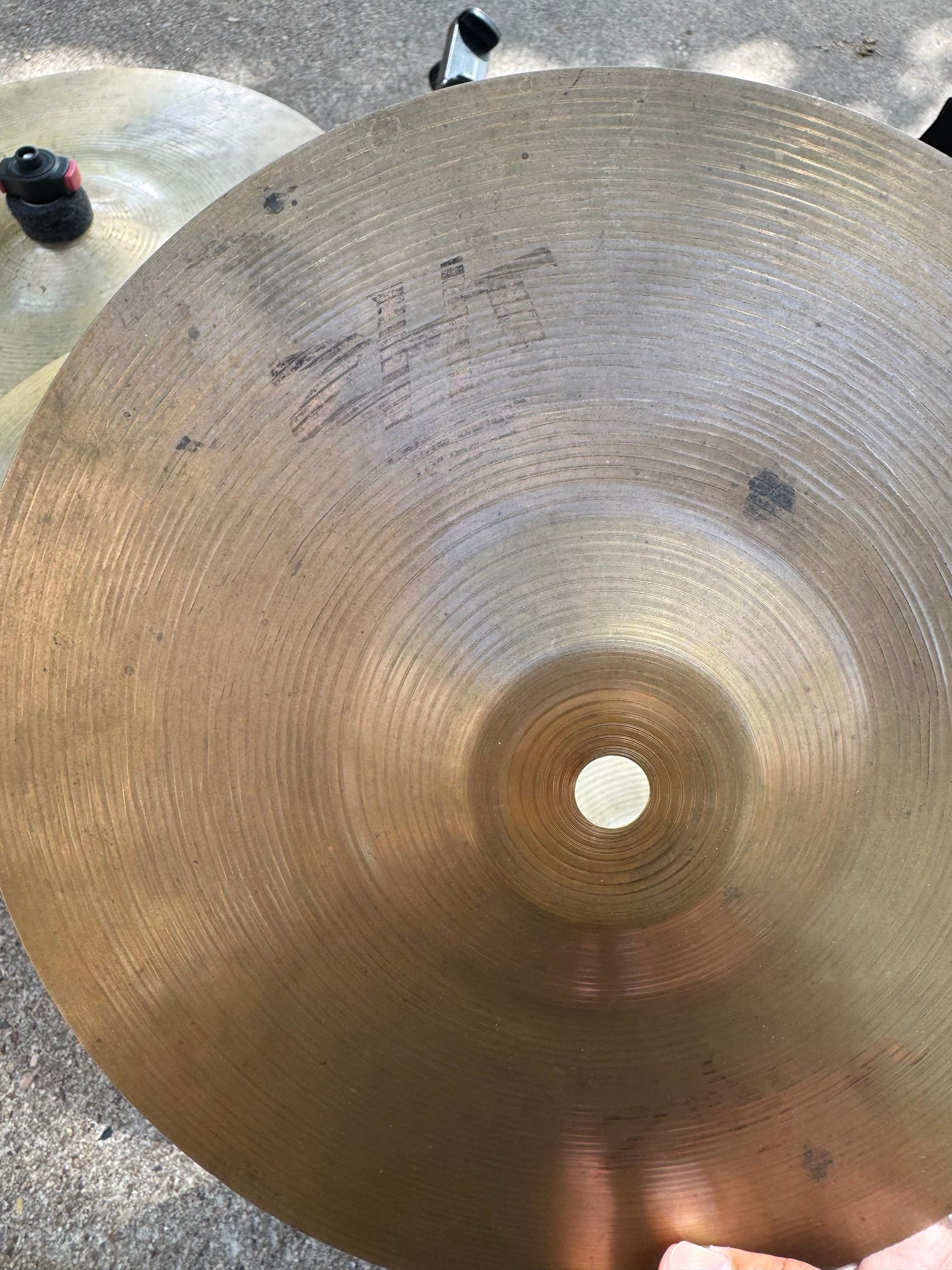 Close-up of a worn cymbal with a partly faded Zildjian ZHT logo.