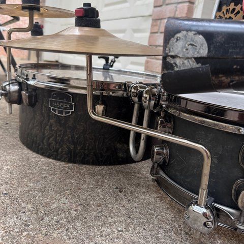 A long bent rod running from a clamp on the snare to the hi-hat between the snare and the floor tom.