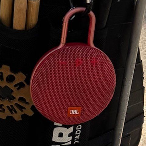 A red round JBL speaker clipped to the front of the harness.