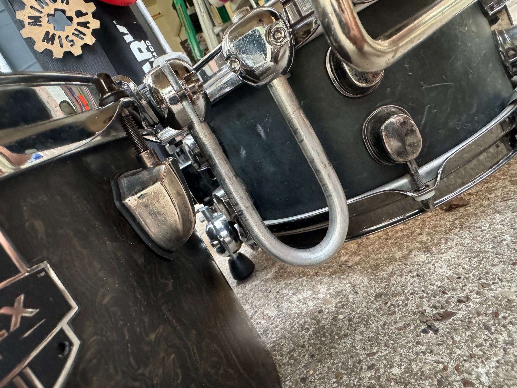 A U-shaped aluminum rod linking a clamp on the snare hoop and a clamp on the floor-tom hoop.